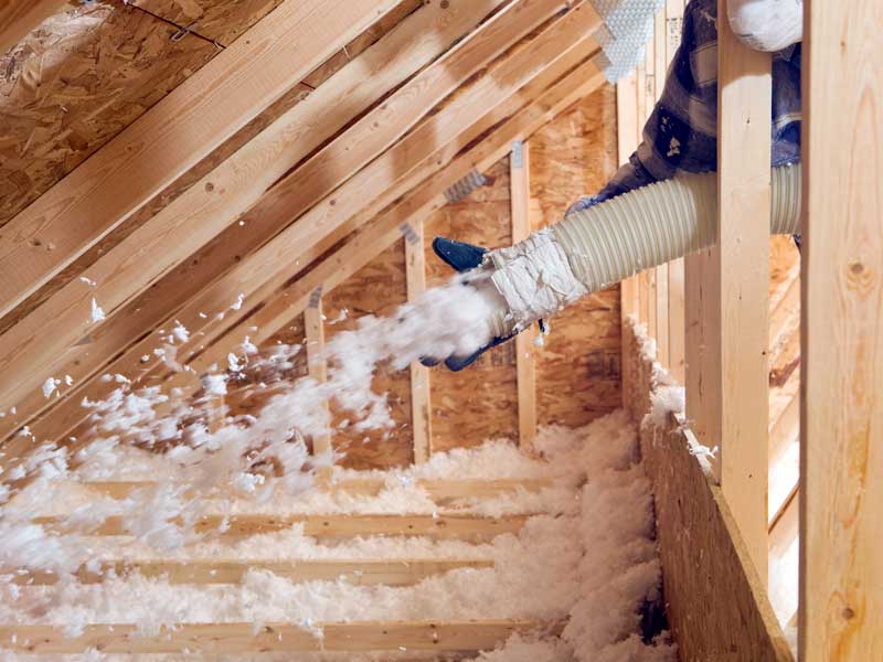 Insulation installer, insulating home's attic with blown-in insulation.