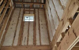 Fiberglass batt insulation installed in tall wall framing near window. Fiberglass batt insulation installed in tall wall framing near window.